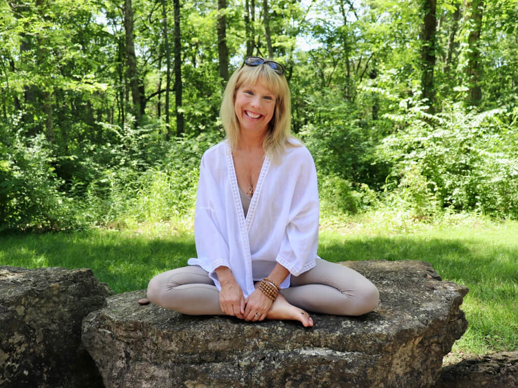 Regan sitting on rock with crossed legs and smiling